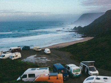 a group of campers parked on a beach next to the ocean