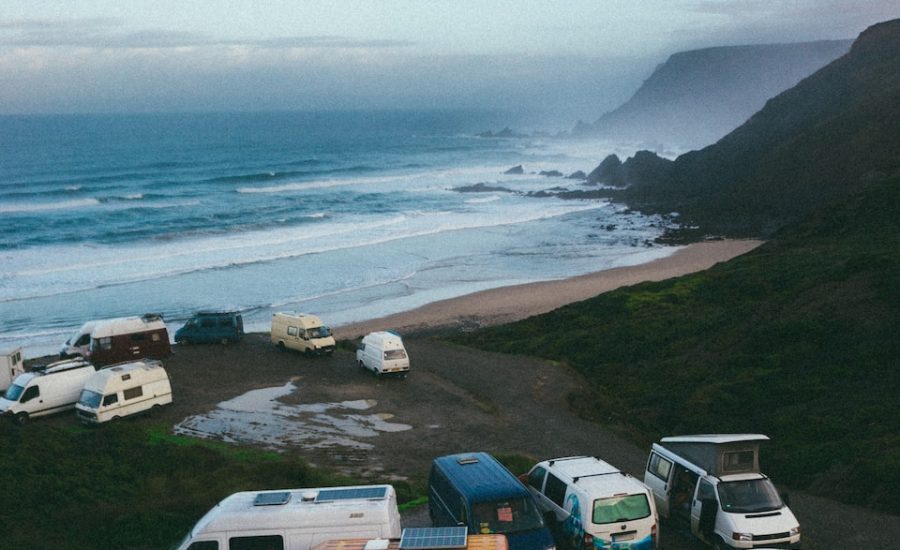 a group of campers parked on a beach next to the ocean